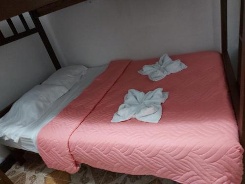 a pink bed with two white towels on it at Hostal Posada Del Corazón in Salento