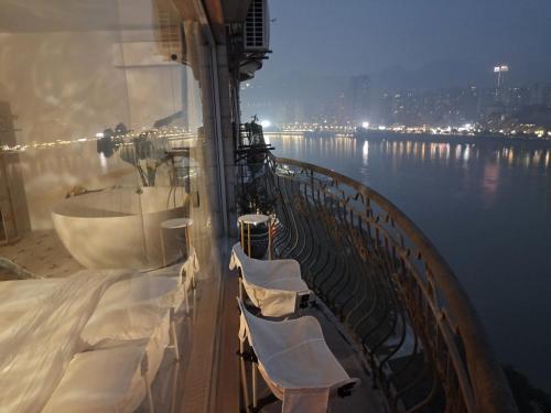 un balcón con sillas blancas en un crucero en Comacros - Chongqing JieFang Cave River View Apartment - Line 1 and Line 2 Jiachangkou Subway Station, en Chongqing