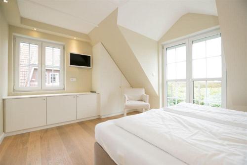 ein weißes Schlafzimmer mit einem Bett und einem Stuhl in der Unterkunft Haus Alster 2 in Westerland