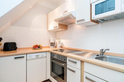 a kitchen with white cabinets and a sink at Haus-Gotland-Wohnung-10 in Westerland