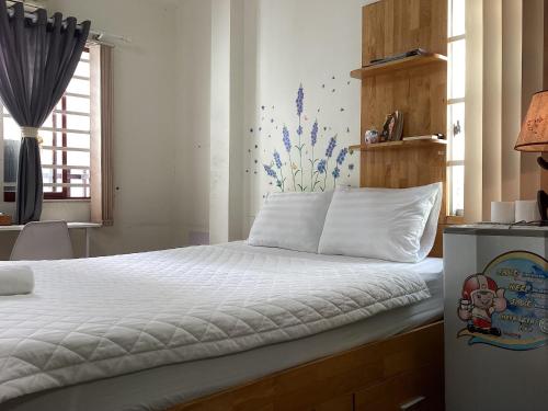 a bedroom with a bed with white sheets and a window at Guest House UTTRANG in Ho Chi Minh City