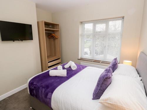 1 dormitorio con 1 cama grande con sábanas moradas en Hazel Cottage, en Keighley