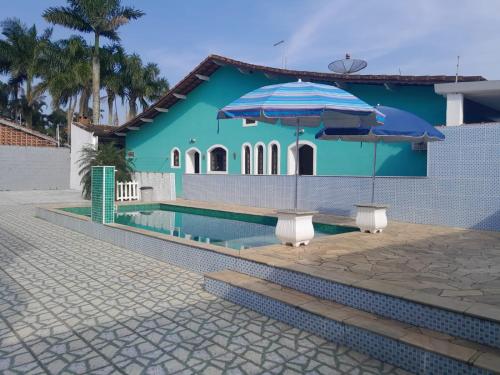 a blue house with a pool and two umbrellas at Itanhaem - Casa com Piscina in Itanhaém