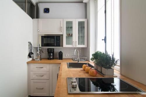 una cocina con armarios blancos y fregadero en My Nest Inn Paris Mouffetard - 30m2 - 200m du jardin des Plantes, en París