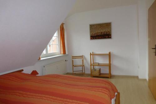 FeWo Ostseerose - DHH 4 في بريرو: غرفة نوم مع سرير برتقالي في العلية