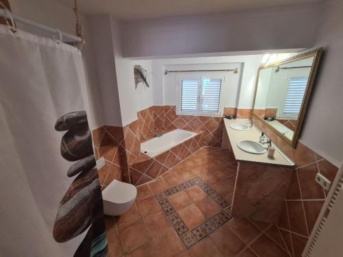 a bathroom with a tub and a sink and a mirror at Amena Mar Hotel in Sa Coma