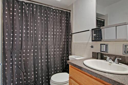 a bathroom with a shower curtain with a toilet and a sink at Tranquil 2BR Escape in Ideal Location - Church 301 in Evanston