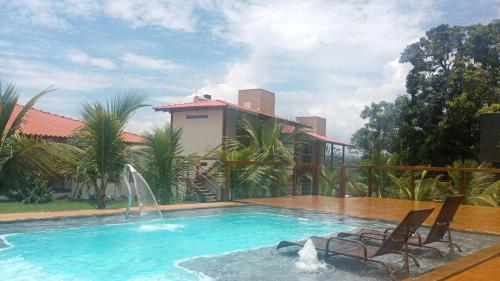 a swimming pool with two chairs and a house at Pousada São José na Canastra in Delfinópolis