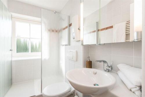 a white bathroom with a sink and a toilet at Tunghoern-Hues-1-OG-Wohnung-03 in Keitum