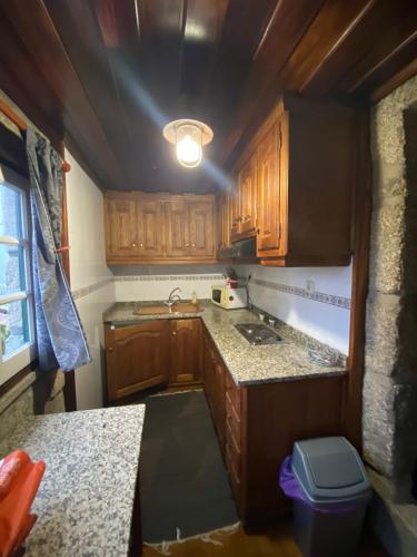 a small kitchen with wooden cabinets and a sink at Casa penedo do bento in Soajo