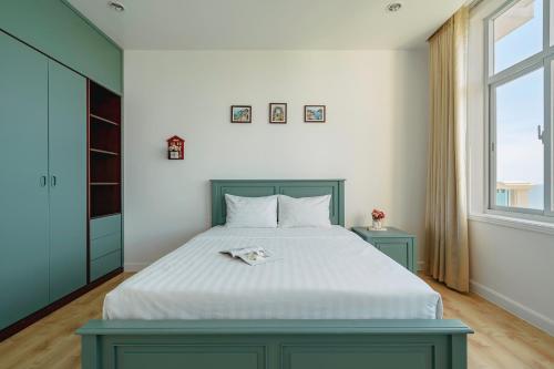 a bedroom with a bed with white sheets and a window at Casa Home - Ocean Melody - Beach Front 3br Apartment in Phan Thiet