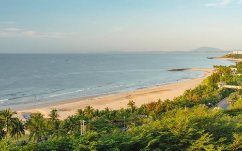 a view of a beach with palm trees and the ocean at Casa Home - Ocean Melody - Beach Front 3br Apartment in Phan Thiet