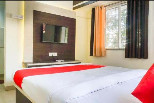 a bedroom with a large white bed and a television at The Guest house in Pune