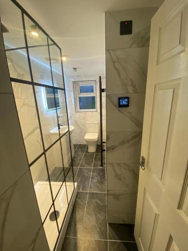 a bathroom with a glass shower and a toilet at The Cwtch, Log Fire, Sleeps 5, Nr Zip World, Brecon and Bike Park Wales in Aberdare