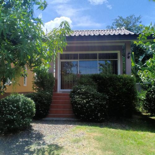 a small yellow house with stairs leading to the front door at Minton Resort มิลตั้น รีสอร์ท in Hat Yai