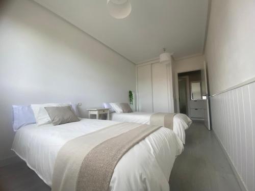 - 2 lits dans une chambre aux murs blancs dans l'établissement Casa cerca de la playa, à Urduliz