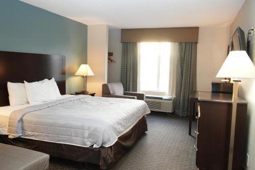 a hotel room with a bed and a chair at Copley Inn & Suites, Copley - Akron in Akron