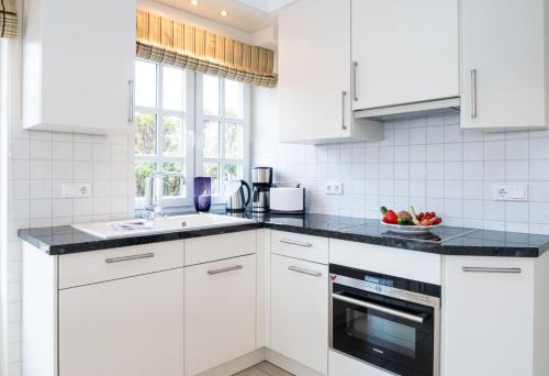 a kitchen with white cabinets and a black counter top at Haus-Fili-Wohnung-2-EG in Wenningstedt
