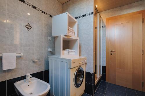 a bathroom with a washing machine and a sink at Alpenvilla Winklwiese in Valdaora
