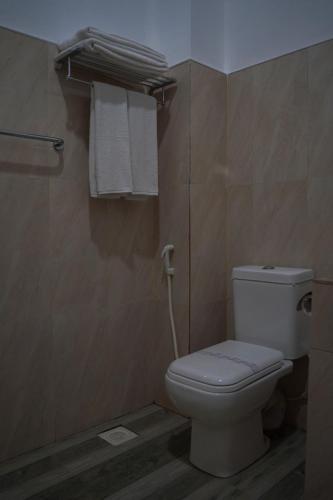a bathroom with a white toilet and towels at Sigiriya Cottage in Sigiriya