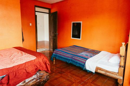 San Rafael的住宿－Hotel IntyKucha，橙色墙壁客房的两张床