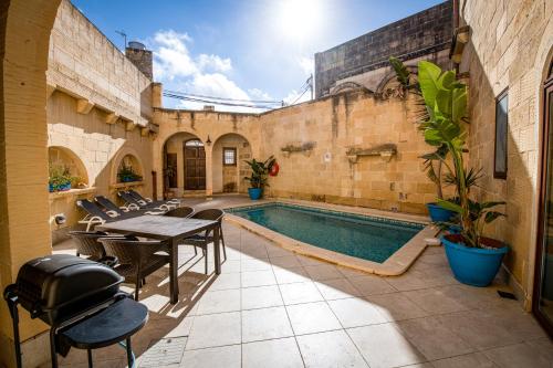 a swimming pool with a table and chairs next to a building at 4 Bedroom Farmhouse with Large Private Pool in Xewkija