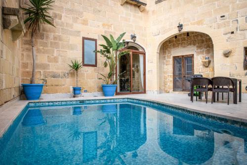 a swimming pool in a house with a stone wall at 4 Bedroom Farmhouse with Large Private Pool in Xewkija