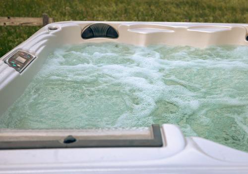 a bath tub filled with water in the grass at Newly built cottages with jacuzzy and sauna in Älmhult
