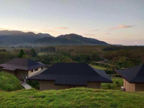 a house on a hill with mountains in the background at Khaolak Blue Sky Villa in Khao Lak