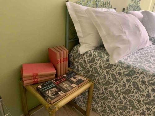 Una cama con una mesa con libros. en Appartamento Cagliari centro con vista sul porto, en Cagliari