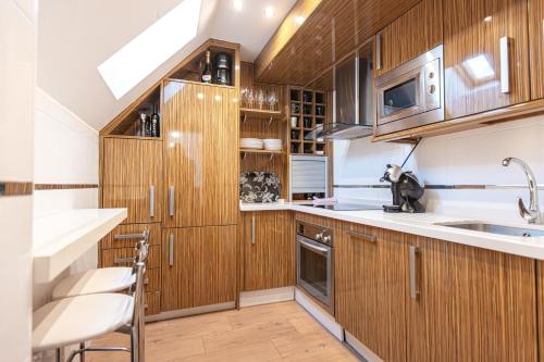 Una cocina con gabinetes de madera y un fregadero. en Duplex lujo Monte Oiz 4 habitaciones y 2 plazas de parking, en Sierra Nevada