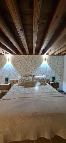 a bedroom with a large bed with two lights on the wall at Beit El Ezz - la petite in Ouled Yaneg