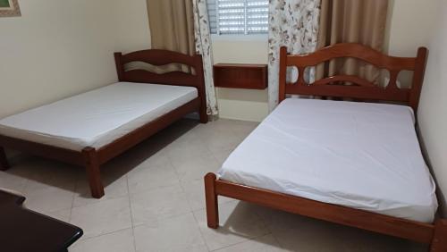 Duas camas num pequeno quarto com uma janela em Sitío Paraíso em Jambeiro