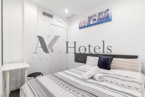 a white bedroom with a hotel sign on the wall at AYZ Ulises - Auto check-in property in Madrid