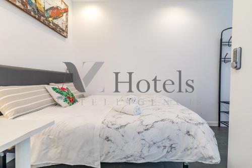 a white bedroom with a bed and a sign on the wall at AYZ Ulises - Auto check-in property in Madrid