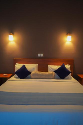 a bed with blue and white pillows and two lights at Sigiriya Cottage in Sigiriya