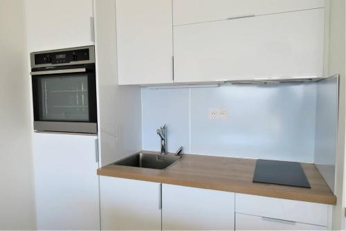 une cuisine blanche avec un évier et un micro-ondes dans l'établissement Bel appartement rénové VUE MER au port de de PERROS-GUIREC Ref 841, à Perros-Guirec