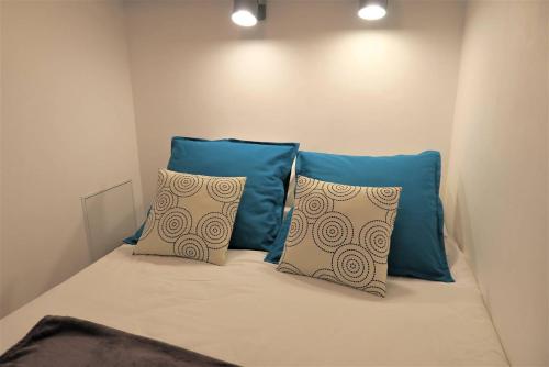 un lit avec deux oreillers bleus dessus dans l'établissement Bel appartement rénové VUE MER au port de de PERROS-GUIREC Ref 841, à Perros-Guirec