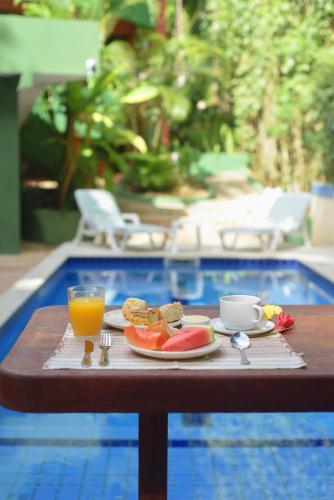 - une table avec un plateau de nourriture et un verre de jus d'orange dans l'établissement Pousada Sonhos de Praia, Fácil Acesso a Praia, Rua Mucugê e Beco das Cores, à Arraial d'Ajuda