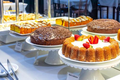 a display of cakes on plates on a table at Luz Hotel by Castelo Itaipava in Foz do Iguaçu