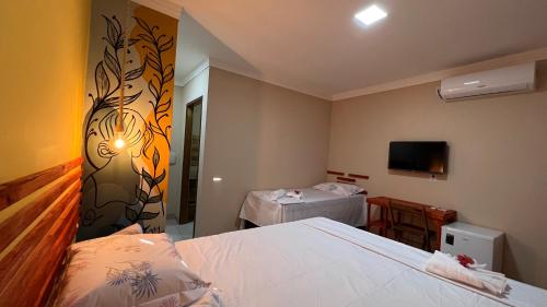 a bedroom with a bed and a table and a tv at POUSADA DONNA MARIA in São Miguel do Gostoso