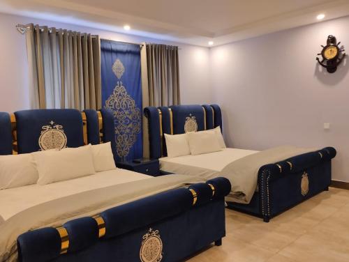 two beds in a room with blue and gold at Islamabad Travelodge Guest House in Rawalpindi