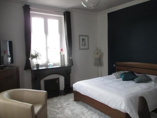 a bedroom with a bed and a chair and a window at Hôtel Le Saint Martin in Sablé-sur-Sarthe