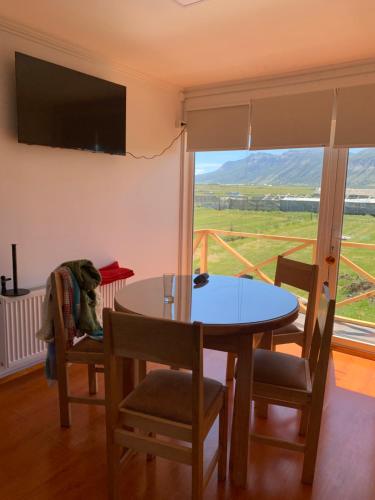 a dining room with a table and chairs and a large window at Cabañas Patagonia Encantada in Puerto Natales