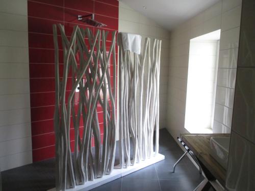 a bathroom with a red wall with wooden sticks on the wall at Hôtel Le Saint Martin in Sablé-sur-Sarthe