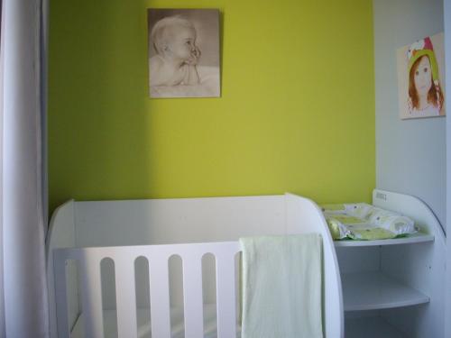 a green room with a crib and a picture of a baby at Hôtel Le Saint Martin in Sablé-sur-Sarthe