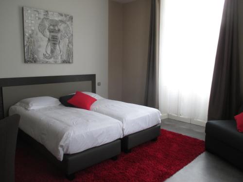 a bedroom with a bed and a red rug at Hôtel Le Saint Martin in Sablé-sur-Sarthe