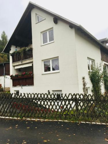 uma casa branca com janelas e uma cerca em Hartensteiner Straße 14 em Lößnitz