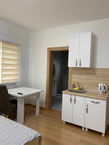 a kitchen with white cabinets and a table and a sink at Apartmani Bella in Krževići