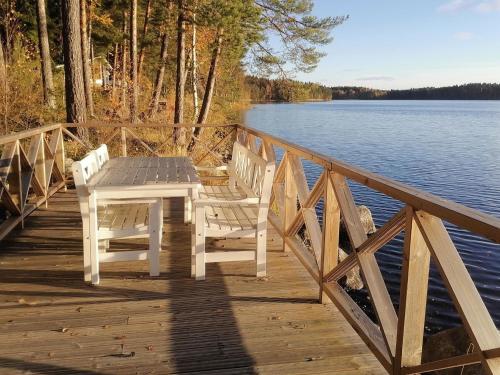 uma mesa e duas cadeiras numa doca de madeira junto à água em Holiday Home Linnusmaa by Interhome em Torvoila